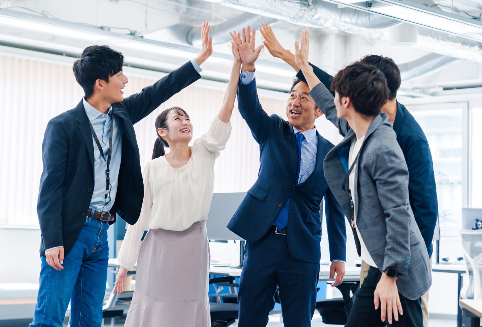 社員5人がハイタッチしようとしている様子